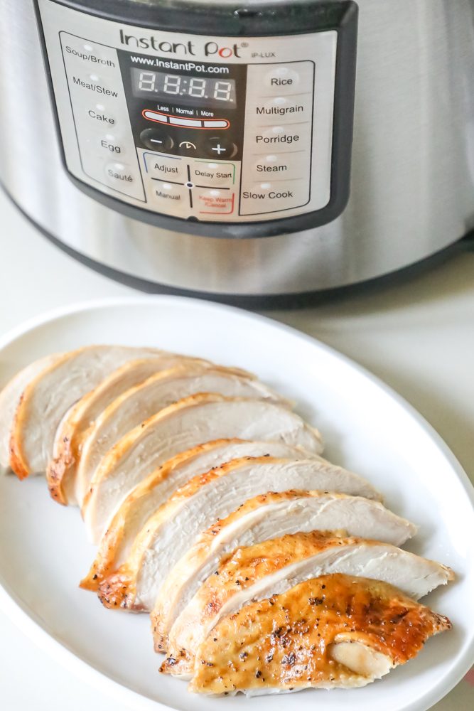 picture of sliced turkey breast in front of instant pot on a white plate