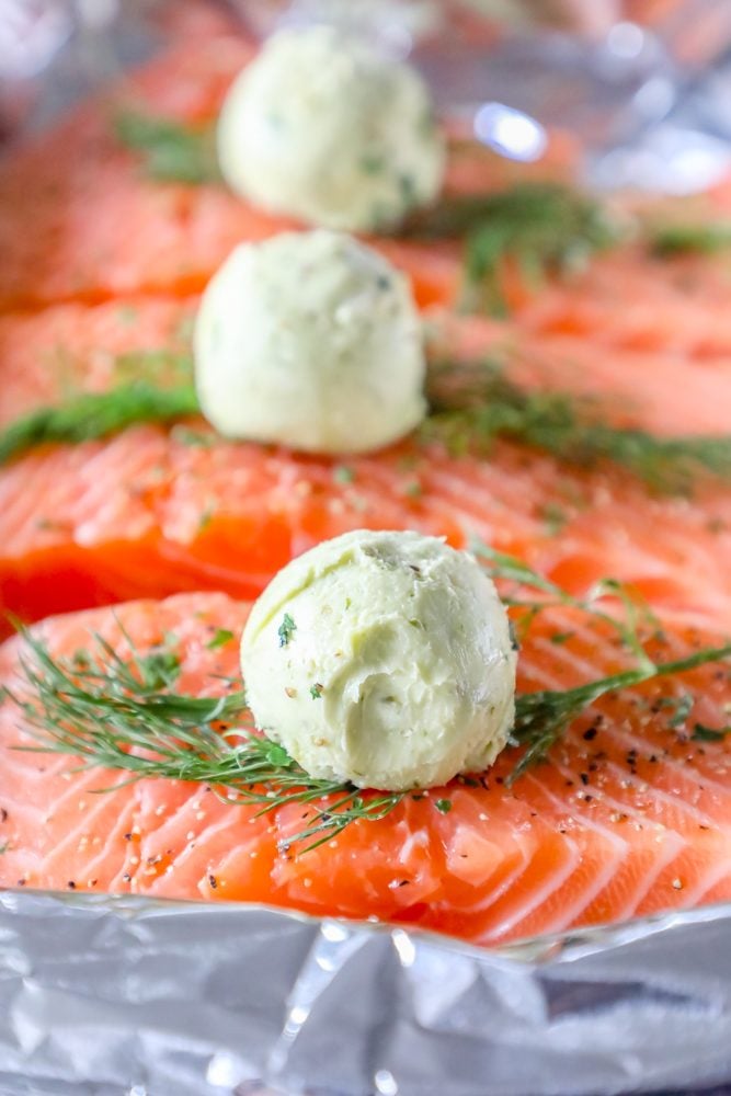 salmon on a tray with butter, pesto, and dill on it and a ball of butter