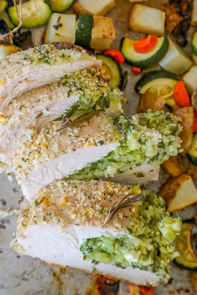 pork loin stuffed with green pesto, zucchini, potatoes, and carrots in the background