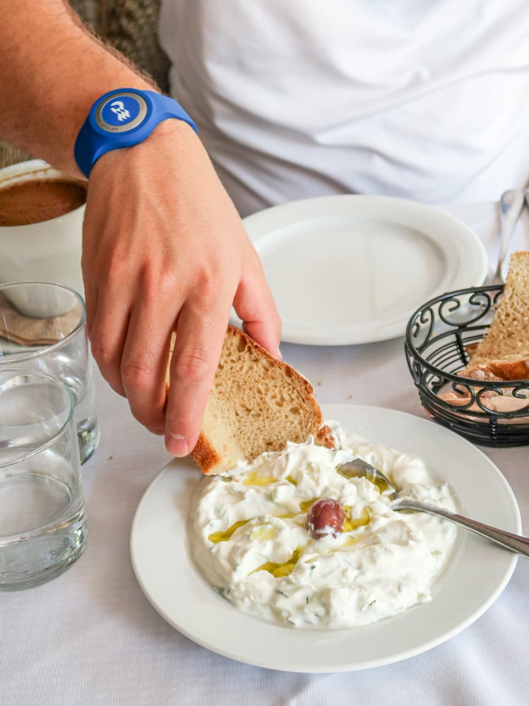 a hand dipping pita into tzatziki 