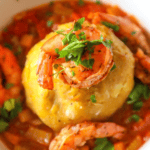 A bowl of food with shrimp and polenta.