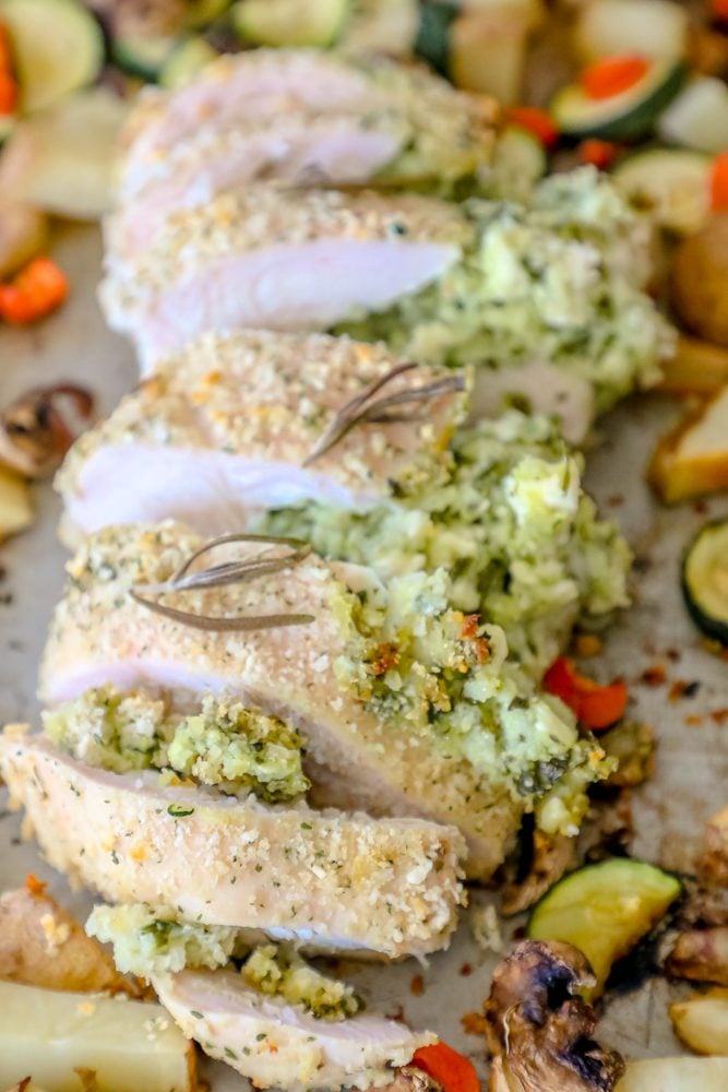 pork loin stuffed with green pesto, zucchini, potatoes, and carrots in the background