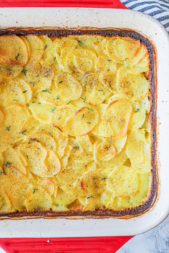 scalloped potatoes in a red casserole dish