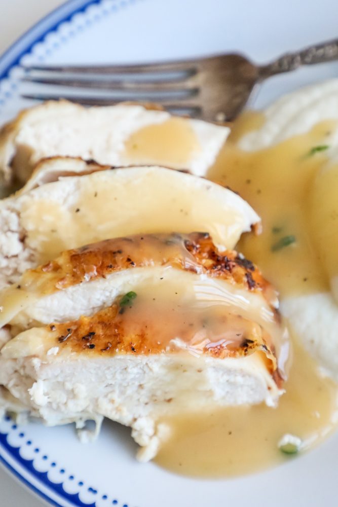 turkey covered in gravy with a fork behind it.
