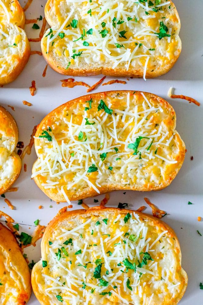 slices of texas toast on a baking sheet with fresh parmesan and cilantro on top 