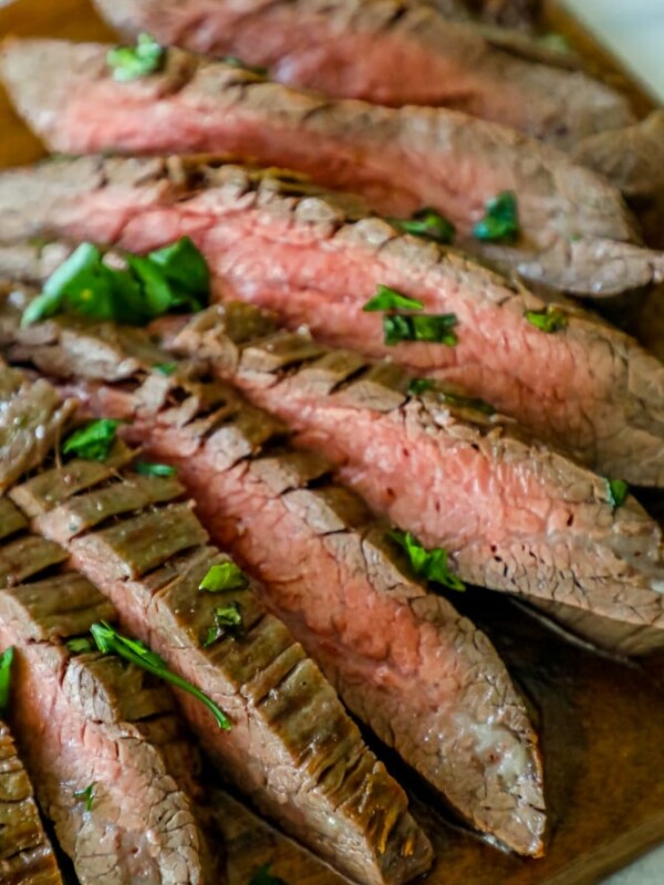 Grilled steak on a wooden cutting board using the garlic butter roasted flank steak recipe.