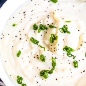 Whipped cauliflower with chives in a white bowl.