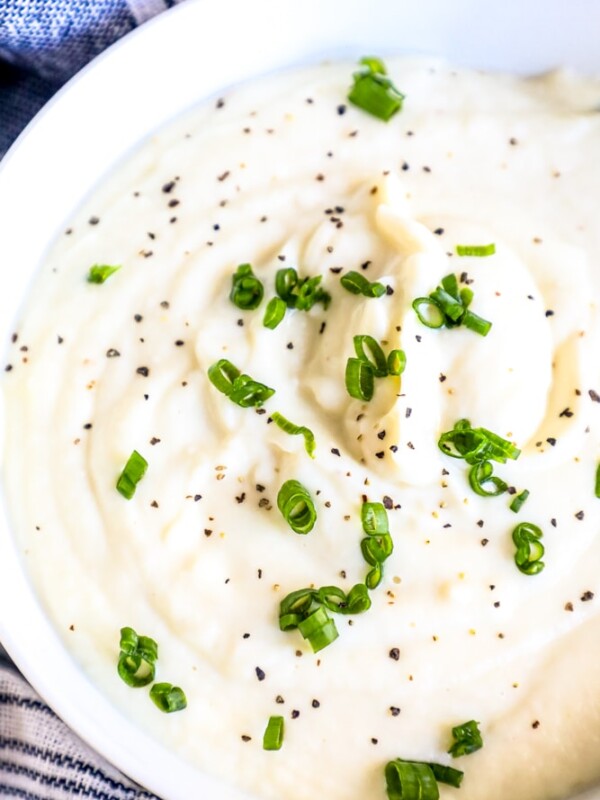 Whipped cauliflower with chives in a white bowl.