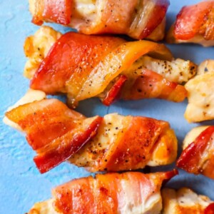 Bacon wrapped chicken skewers on a blue background, with sweet and spicy flavors.