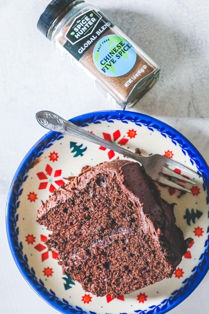 chocolate cake slice on a plate, Chinese five spice in a jar above it.