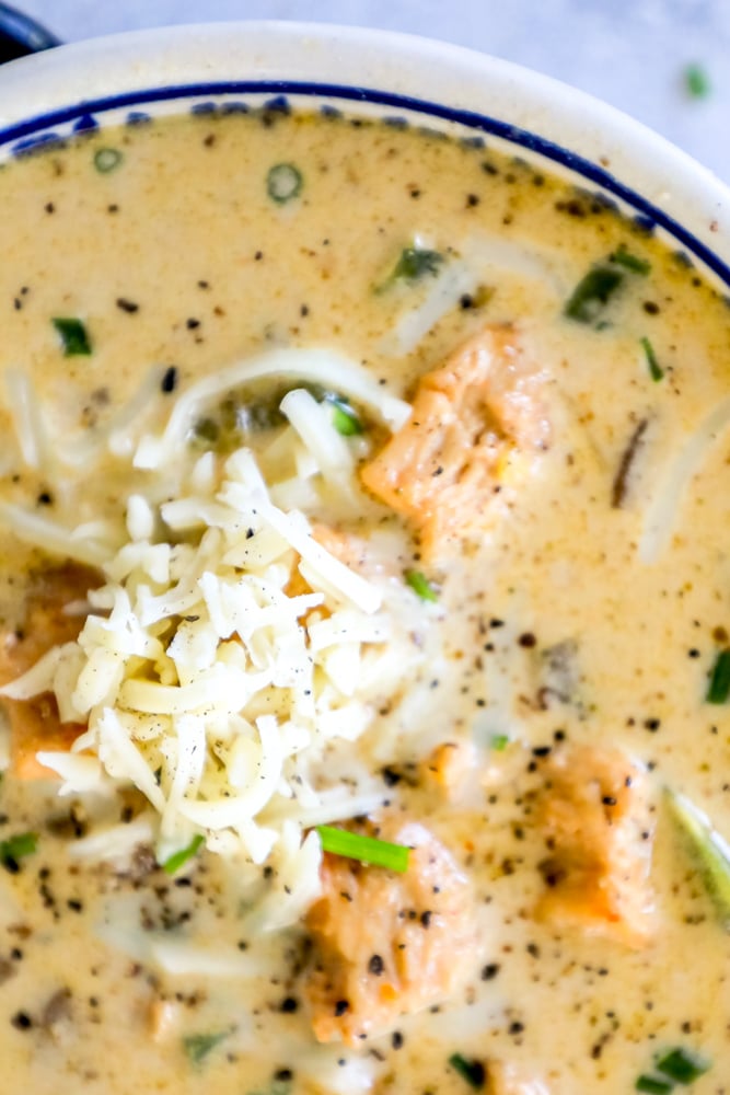 creamy white chicken chili in a bowl topped with shredded cheese