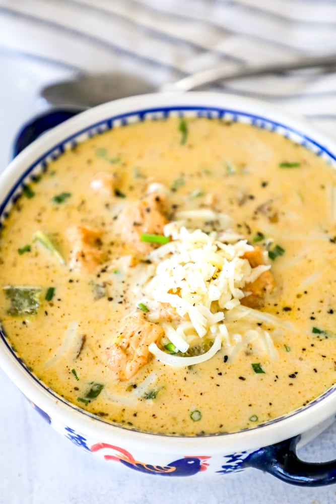 white chicken chili in a bowl with chunks of chicken, chopped bell peppers, and shredded jack cheese on top 