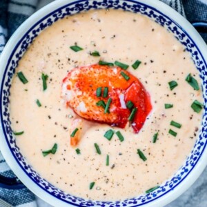 Easy lobster bisque recipe with chives served in a blue bowl.