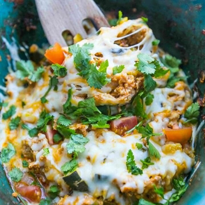 A bowl of Mexican veggie enchiladas with a wooden spoon, inspired by slow cooker chicken tacos.