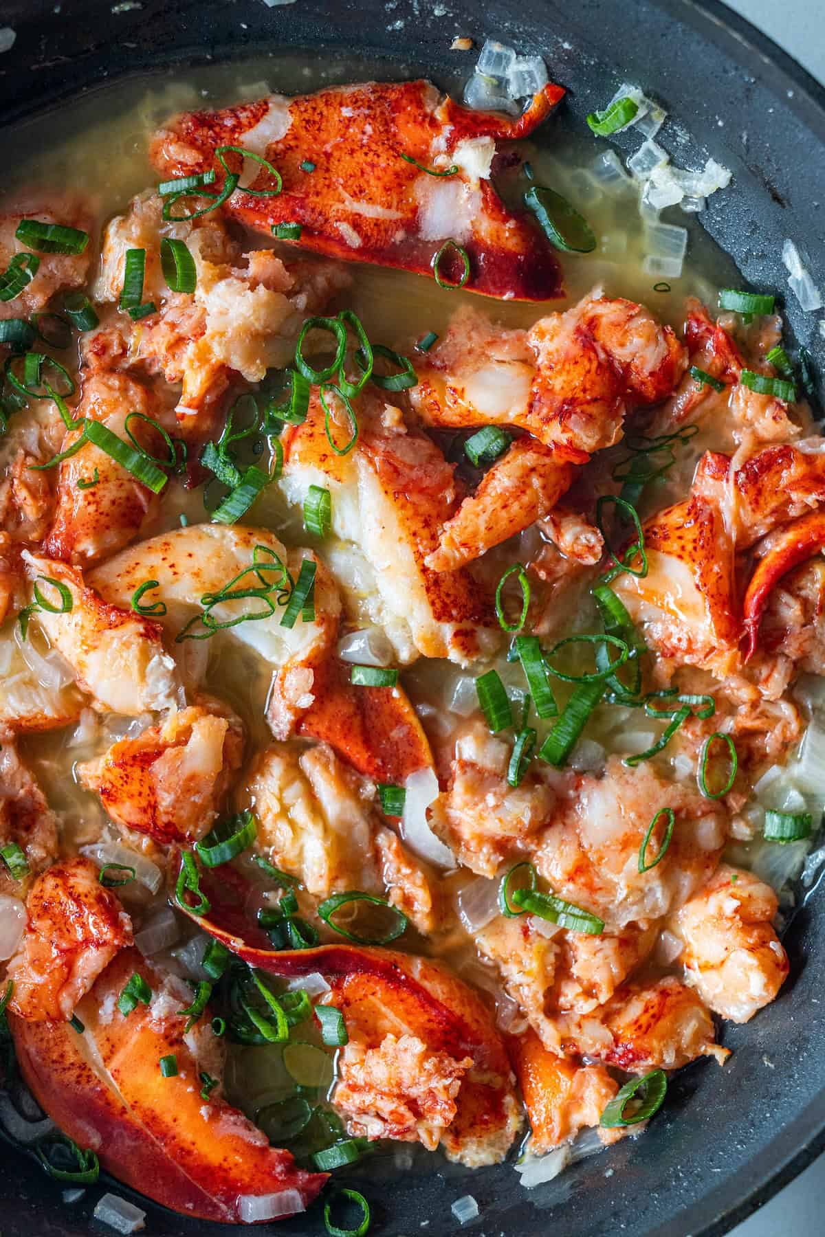 Enjoy an Easy Garlic Butter Lobster Skillet featuring cooked lobster meat sautéed with chopped green onions and diced onions in a rich butter sauce.