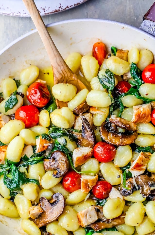picture of gnocchi pasta in pan with mushrooms, diced chicken, tomatoes, and spinach