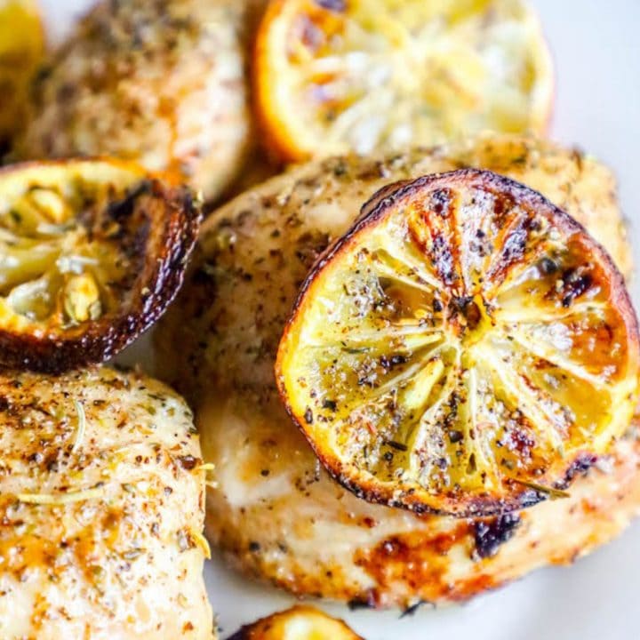 Grilled chicken with lemon slices on a white plate, prepared using an air fryer.