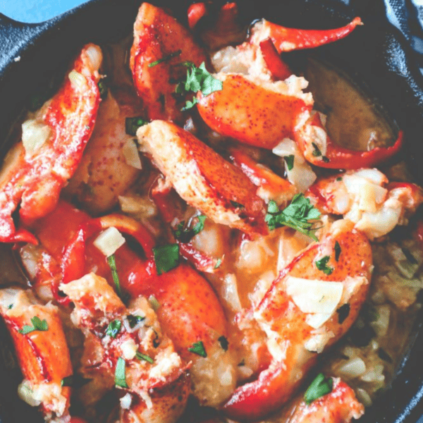 A skillet full of lobster in a buttery red sauce.