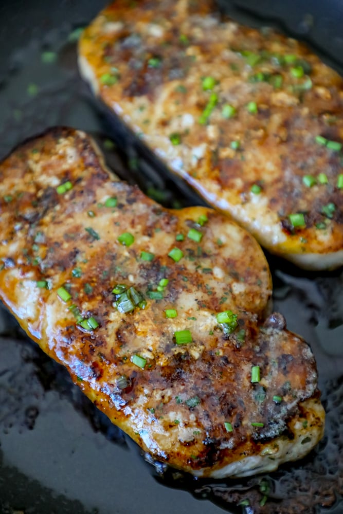 baked ranch pork chops in a pan with chives on top