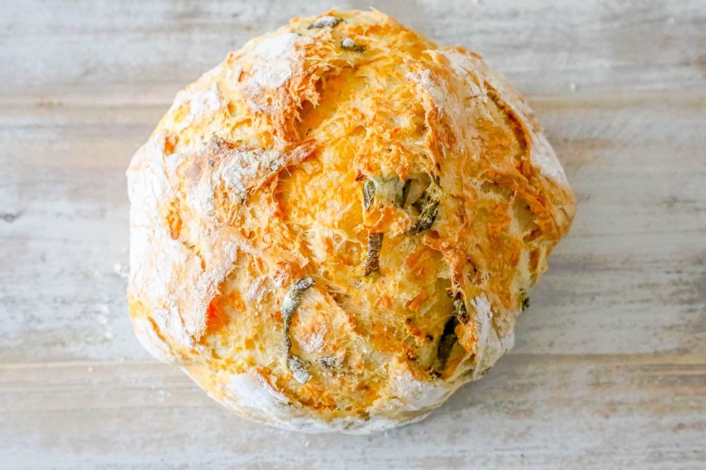 a round bread loaf with jalapeños and cheddar on a table