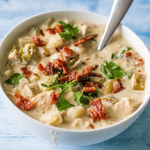 Creamy bacon chicken and potato chowder in a white bowl with a spoon.