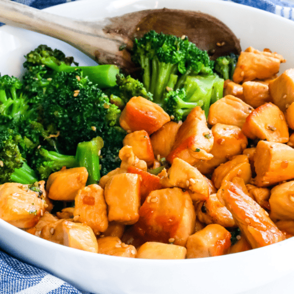Teriyaki Chicken and broccoli in a white bowl with a wooden spoon.