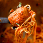 A fork is being used to scoop the best instant pot spaghetti and meatballs out of a pot.