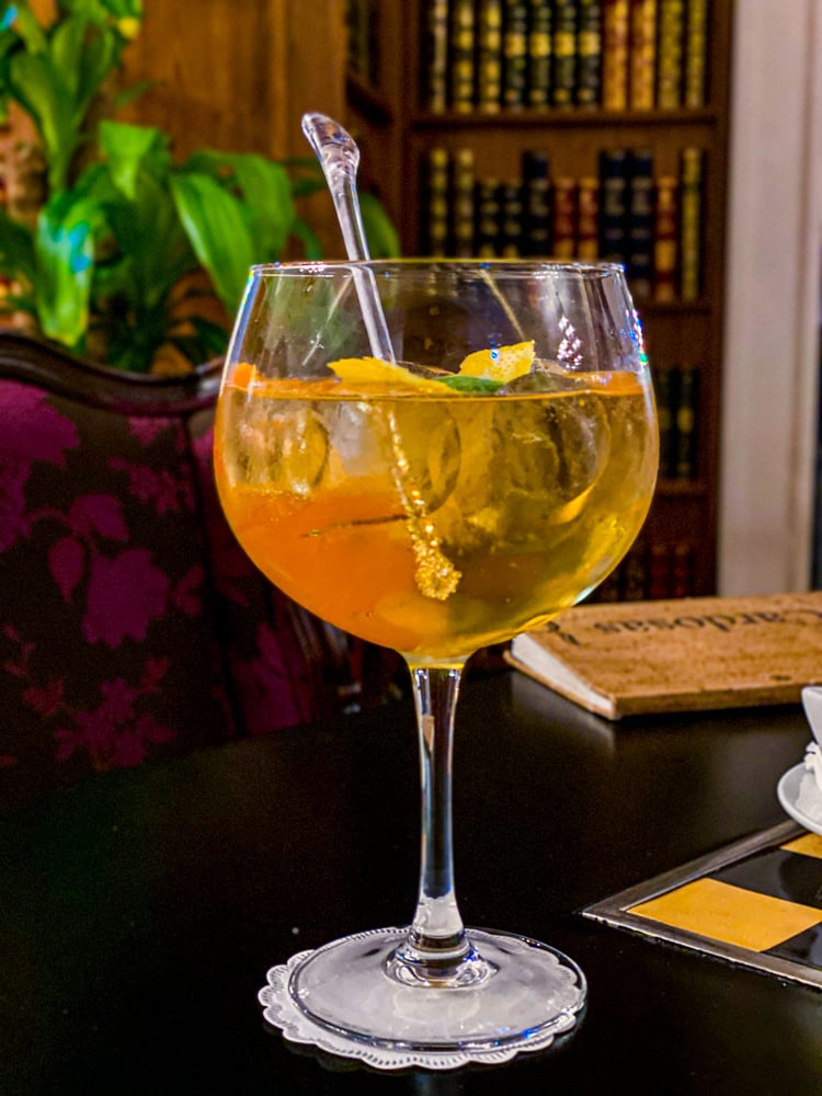 Picture of port and tonic in a wine glass in a hotel lobby bar. 