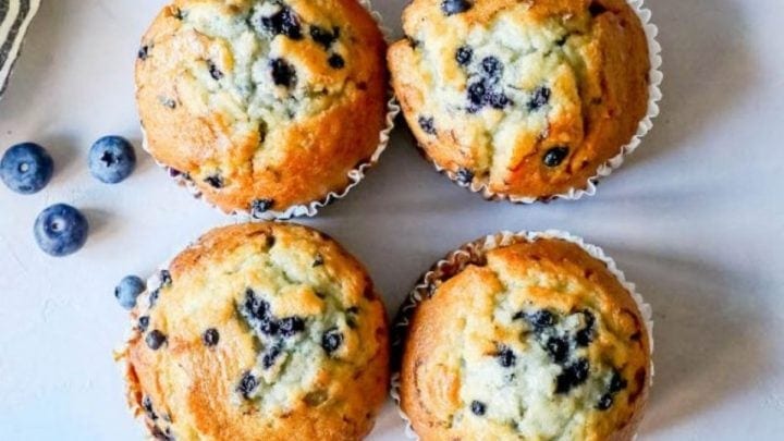 picture of blueberry muffins on a table next to blueberries