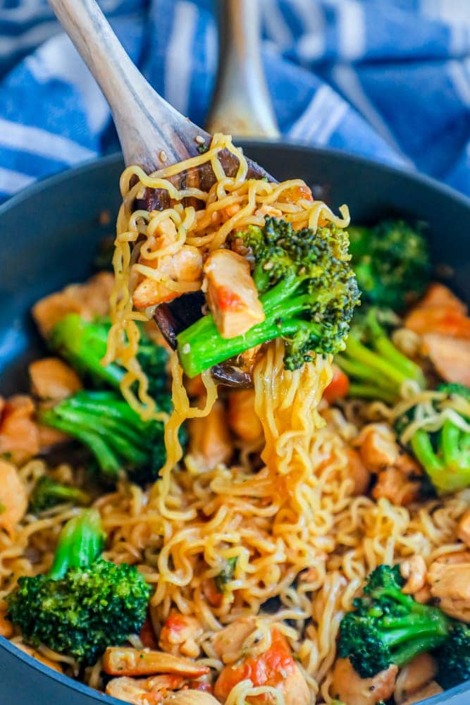 noodles with chicken and broccoli in a pot with a spoon in it