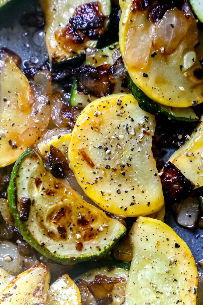 slices of sauteed squash and zucchini in a pan with herbs and pepper 