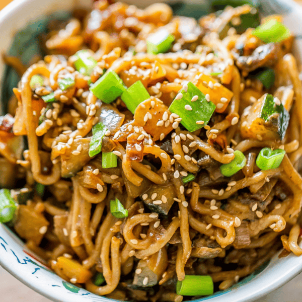 A bowl of creamy tahini noodles topped with sesame seeds, sliced green onions, and stir-fried vegetables—a delicious take on the classic tahini noodles recipe.
