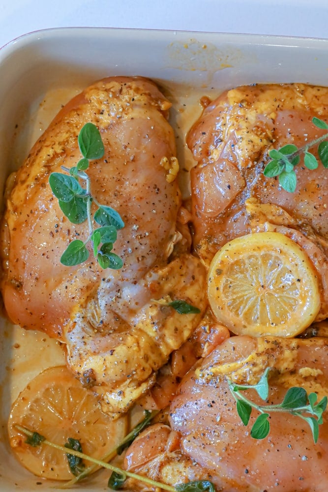 raw chicken thighs marinating with lemons and oregano 
