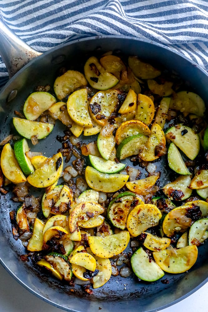 pan with squash and zucchini slices topped with pepper and herbs