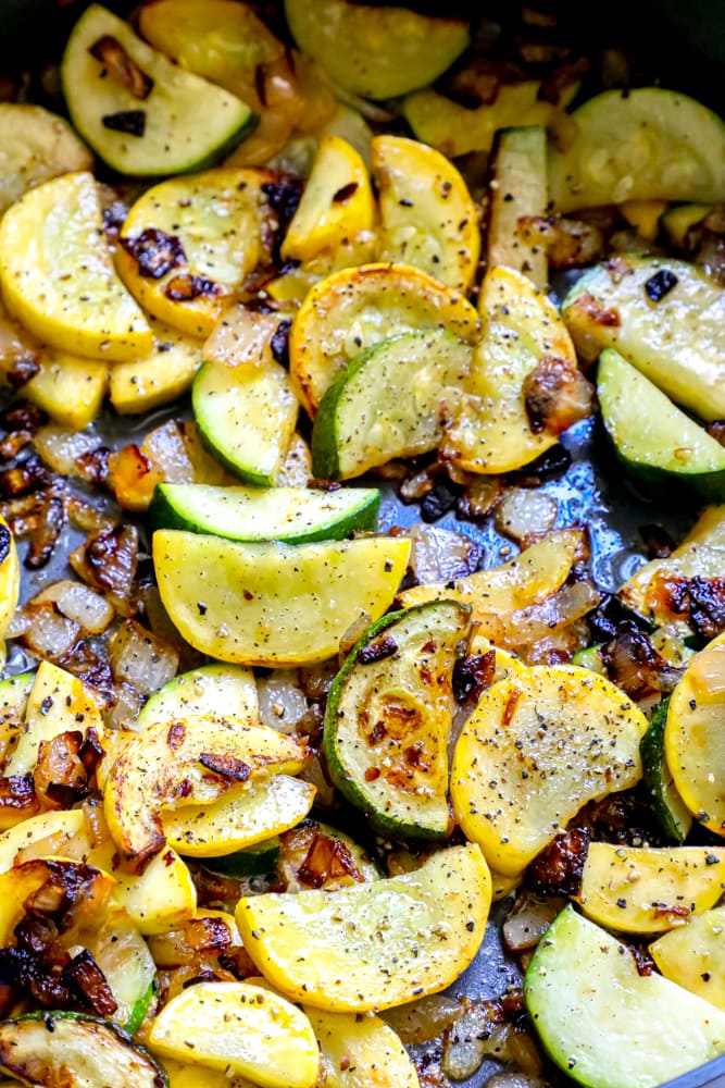 browned zucchini and summer squash with garlic and onion in a pan 