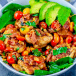 A bowl filled with seasoned BLAT Chicken, cherry tomatoes, spinach leaves, avocado slices, and crumbled bacon.