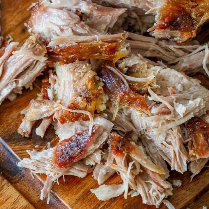 shredded pork shoulder with crispy skin on a cutting board