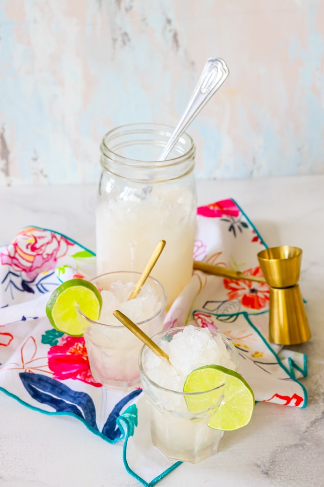 picture of two glasses and a mason jar on a table with slices of lime
