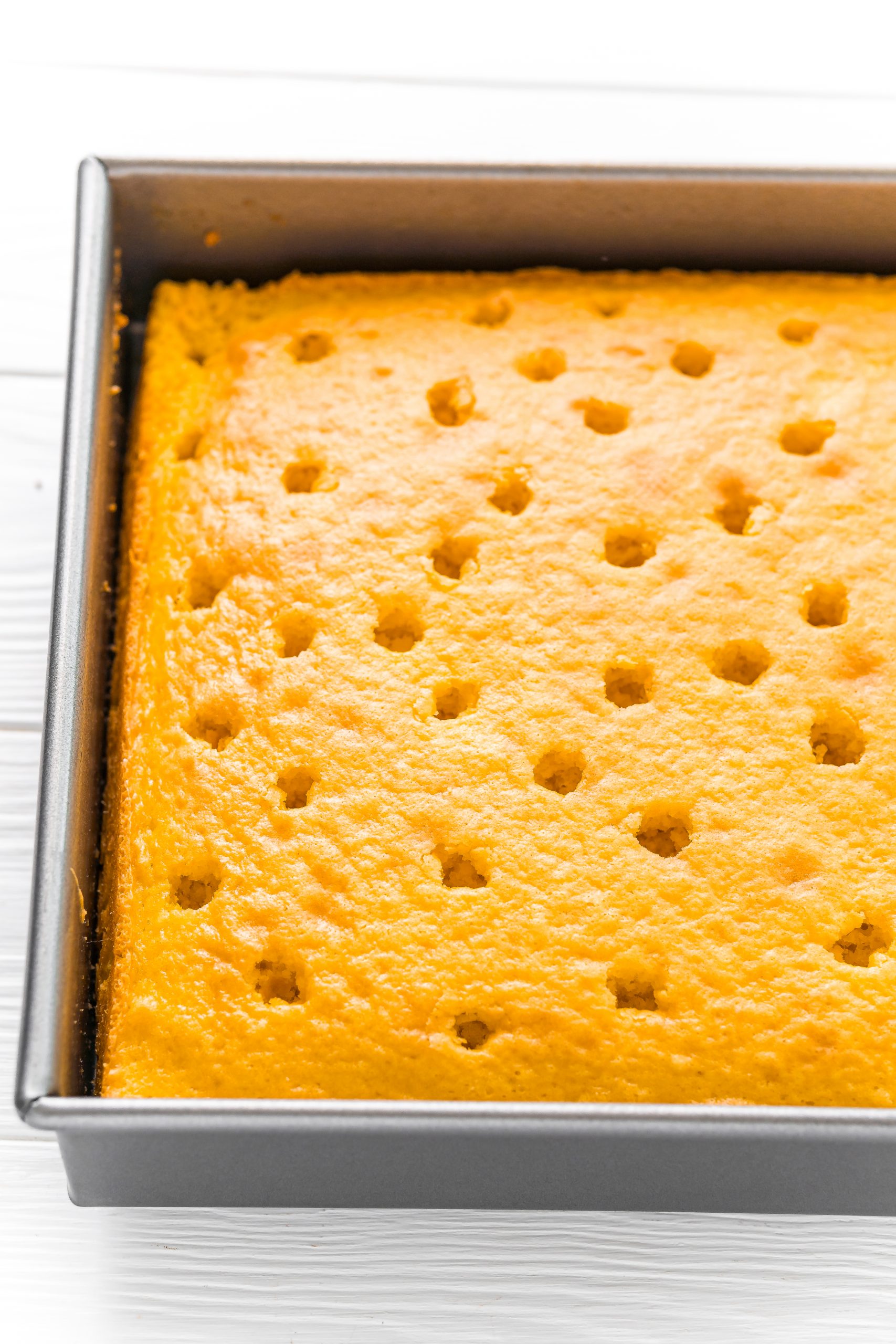 Easy Lemon Jello Poke Cake Recipe with a square cake in a baking pan.