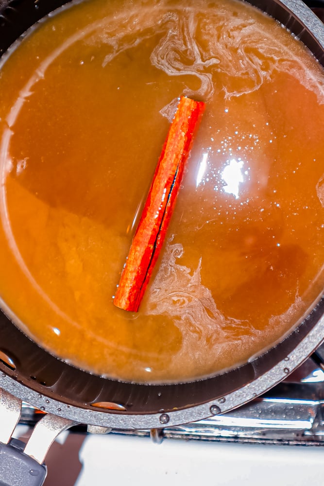 A pot of apple cider with a cinnamon stick in it.