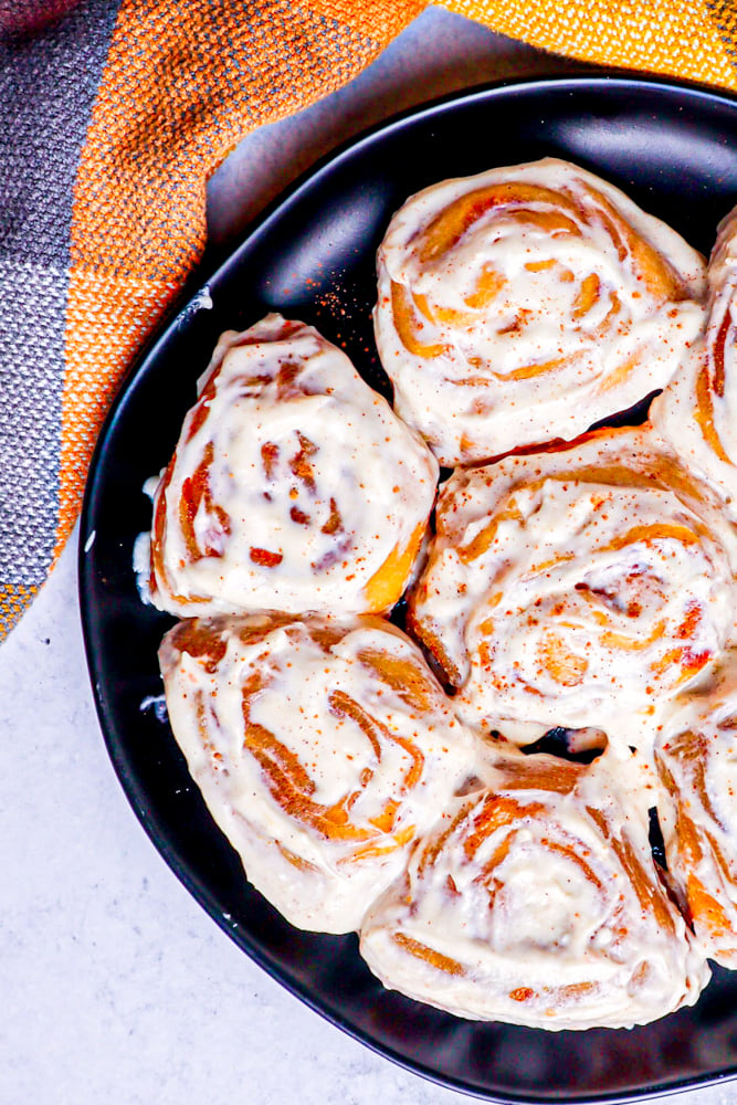 picture of pumpkin cinnamon rolls on a black plate
