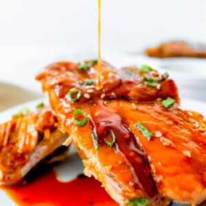 A plate of Instant Pot Asian Sticky Ribs being drizzled with sauce.
