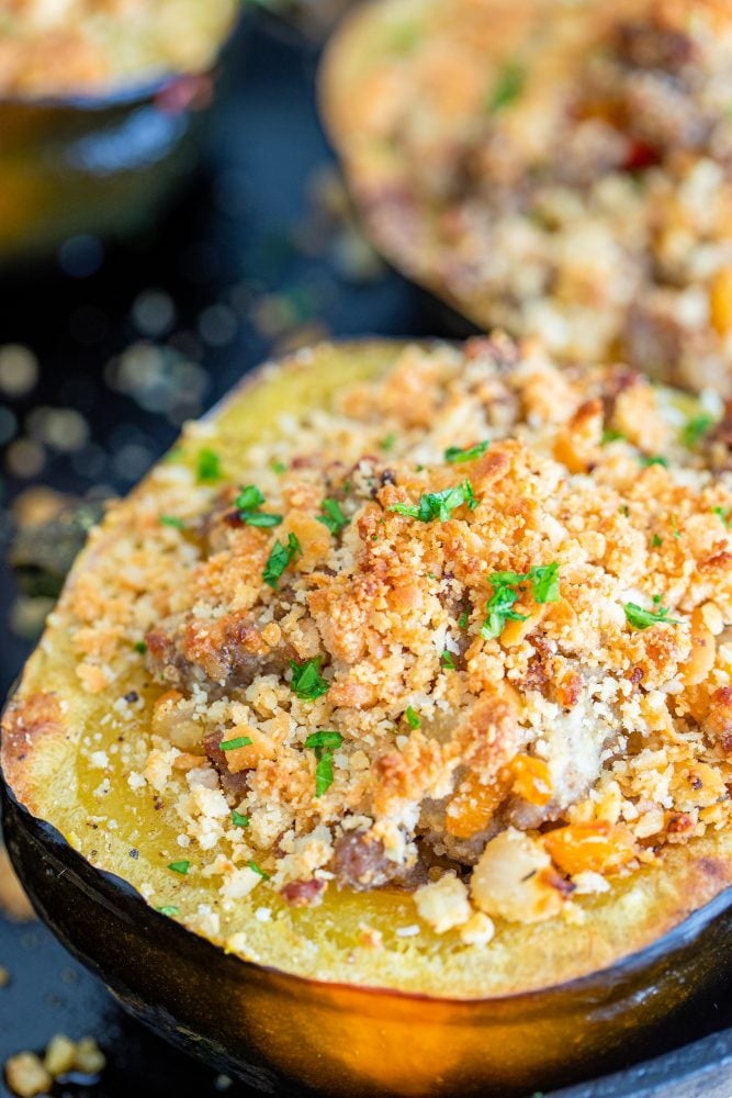 baked acorn squash stuffed with sausage and breadcrumbs on a baking sheet
