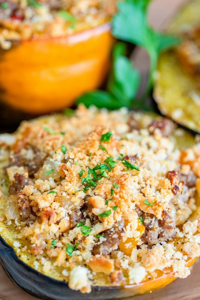 baked acorn squash stuffed with sausage and breadcrumbs on a baking sheet
