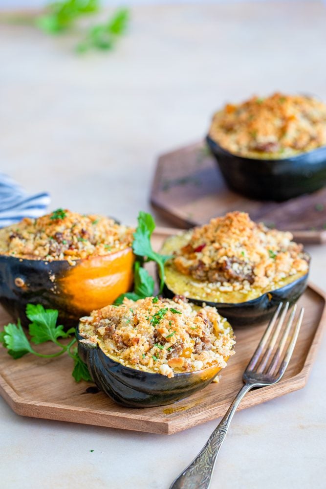 baked acorn squash stuffed with sausage and breadcrumbs on a baking sheet
