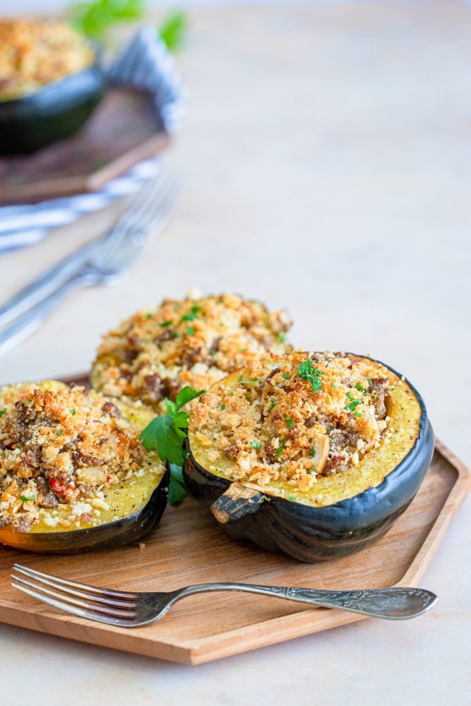 baked acorn squash stuffed with sausage and breadcrumbs on a baking sheet
