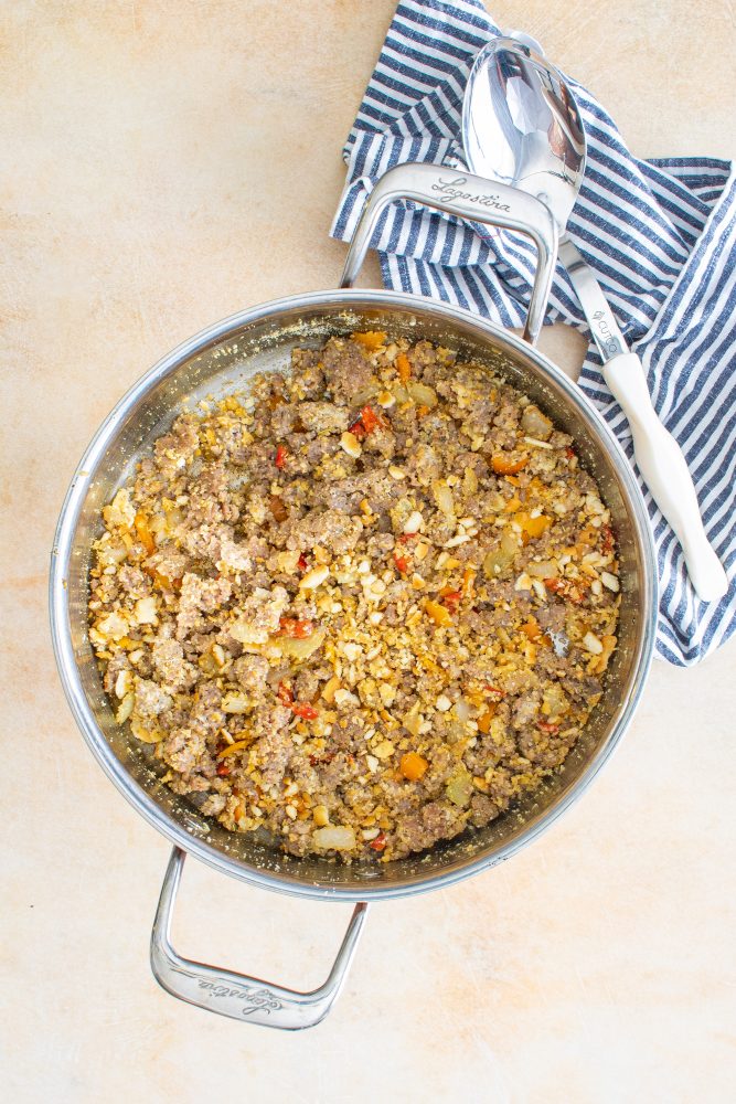 Sausage browning in a pan with diced vegetables, a key step for the stuffing.