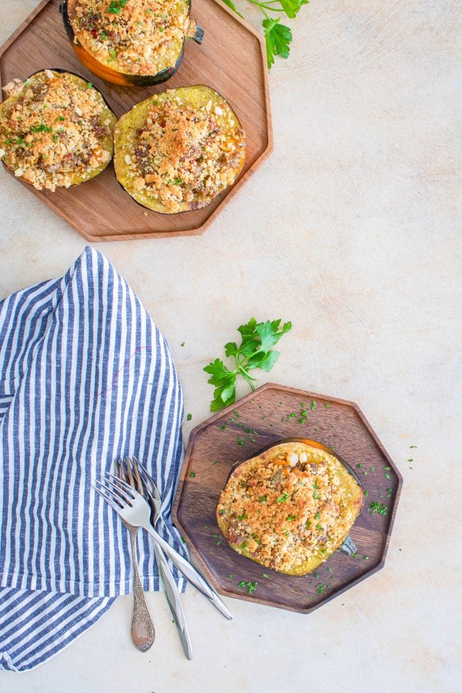 baked acorn squash stuffed with sausage and breadcrumbs on a baking sheet
