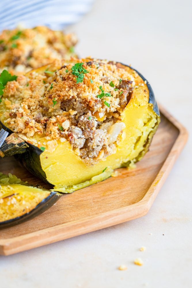 baked acorn squash stuffed with sausage and breadcrumbs on a baking sheet
