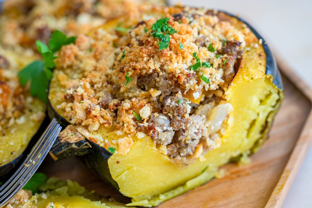baked acorn squash stuffed with sausage and breadcrumbs on a baking sheet
